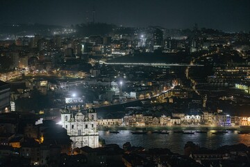 Evening descends on Porto, Portugal. City lights illuminate ancient buildings and Douro River. Tranquil view capturing the essence of Portuguese architecture