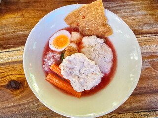 Pink noodles soup with bouncy pork and shrimp balls soft-boiled eggsin pink soupserved in cup. Yentafo buffet is type of noodles. It's like fishball noodles but uses red soup from fermented bean curd.