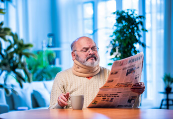 Senior Indian man with newspaper and tea at table during quiet morning routine at home