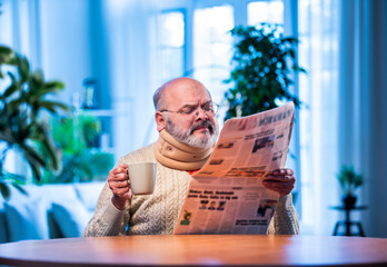 Senior Indian man with newspaper and tea at table during quiet morning routine at home