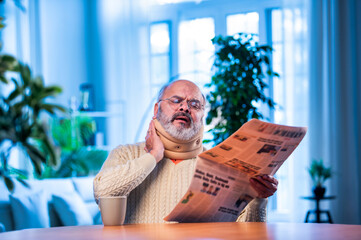 Senior Indian man with newspaper and tea at table during quiet morning routine at home