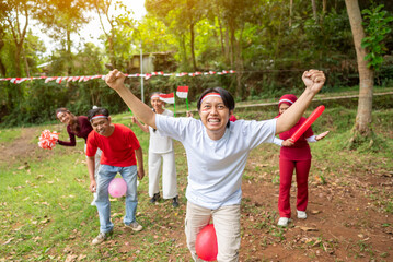 Fototapeta premium Portrait of an Indonesian southeast asian people celebrate Indonesia Independence Day on the 17th of August with a game of keep the balloon from blowing out outdoors. Concept of Kemerdekaan Indonesia