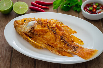 Deep fried red tilapia fish on white plate and dipping sauce