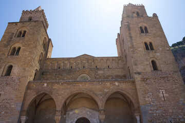 Ancient stone church with twin towers and arched entrance under clear blue sky in historic location