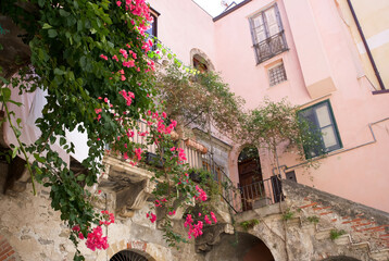 Beautiful pink bougainvillea flowers cascading over a charming Italian balcony in a picturesque...