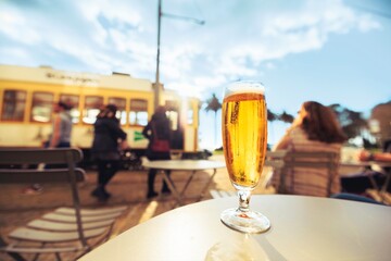 Sunlit afternoon in Porto. Diverse travelers enjoy drinks at a cafe, capturing the essence of relaxation as a vintage tram passes nearby, showcasing the city's unique blend of old and new