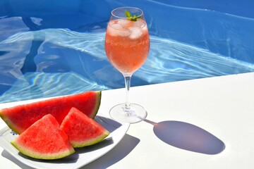 Refreshing cocktail and watermelon slices in the pool. Summer vacation.