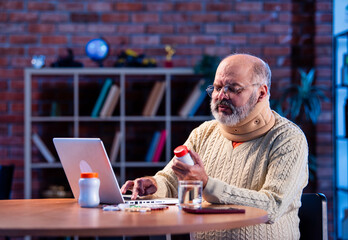 Elderly Asian man researching medicine dosage online at home using laptop