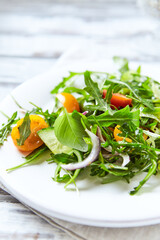 Salad with Tomatoes, Cucumber and Rocket on bright Background. Healthy Snack Idea. Close up.