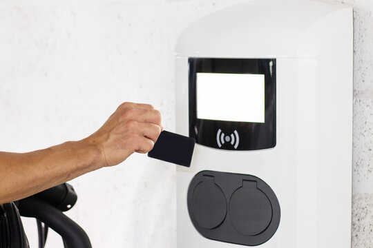 Man uses contactless card to pay at electric vehicle charging station. Highlights seamless payment, innovative technology, green transport solutions, fast charging, and modern urban infrastructure.