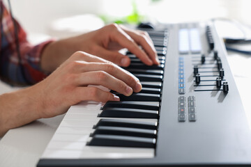 Man working with MIDI keyboard at table indoors, closeup