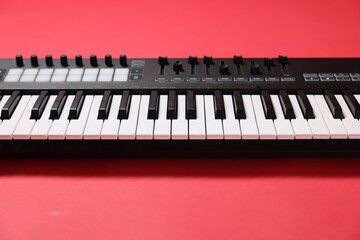 One portable MIDI keyboard on red background, closeup