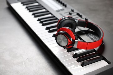 MIDI keyboard and headphones on grey table, closeup
