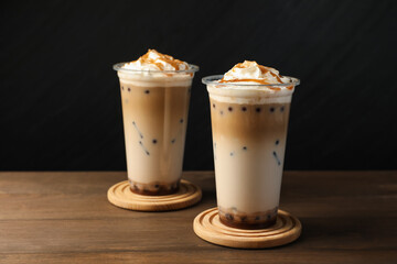 Tasty milk bubble tea in plastic cups on wooden table
