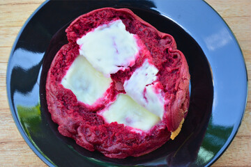 A close-up reveals the rich texture of a red velvet cake roll, generously filled and topped with creamy white frosting, hinting at its deliciousness