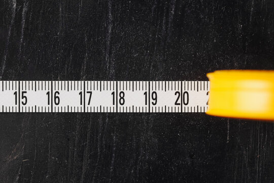 Measuring tape closeup on dark background. Construction tool detail with yellow case. Measurement from fifteen to twenty centimeters. DIY instrument for accuracy and precision. Handy work equipment.