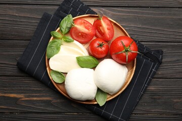 Tasty mozzarella cheese, tomatoes and basil on wooden table, top view