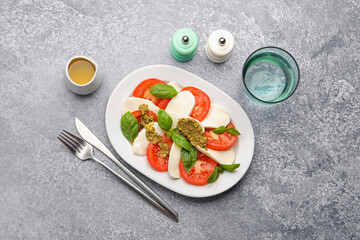 Tasty salad Caprese served with pesto sauce on grey table, flat lay