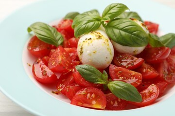 Tasty salad Caprese with mozzarella, tomatoes, basil and spices on table, closeup