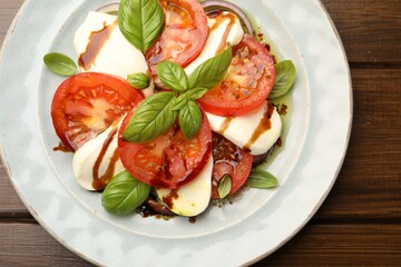 Tasty salad Caprese with mozzarella, tomatoes, basil and spices on wooden table, top view