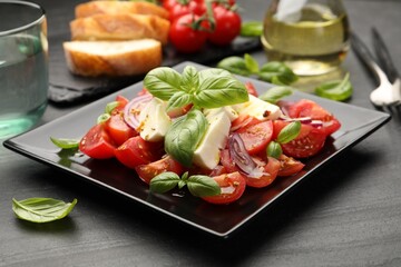 Tasty salad Caprese served on black table, closeup