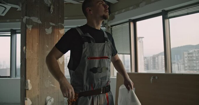 Construction workers discuss blueprints in a dilapidated office space. Renovation, building, and teamwork in the construction industry.