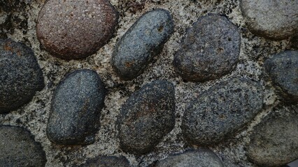 Smooth River Stones Embedded in Textured Mortar CloseUp Detail.