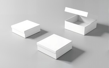 Three pristine white boxes rest on a neutral gray surface, casting subtle shadows. One is closed, another is open, and a third is partially visible. High quality