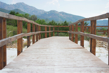 Obraz premium A wooden path at the beach Spiaggia La Cinta in San Teodoro, Olbia, Sardinia