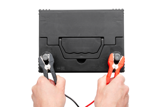 Top view of hands connecting positive and negative terminals of cables to car battery. AGM battery charging and testing concept, cutout, isolated background.
