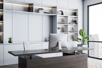 Modern executive office interior with wooden desk, white shelves, and city view through large glass...