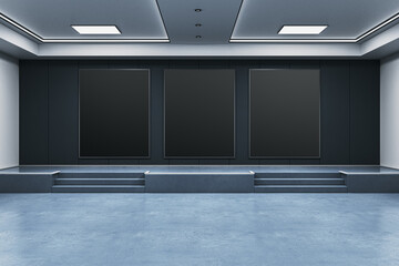 Modern exhibition room with three large black vertical poster frames on a dark wall in a clean...
