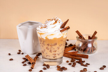 Iced cinnamon latte with whipped cream, cinnamon syrup and cinnamon powder on top, with coffee...