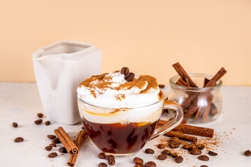 Iced cinnamon latte with whipped cream, cinnamon syrup and cinnamon powder on top, with coffee...