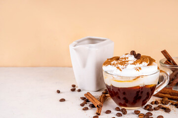 Iced cinnamon latte with whipped cream, cinnamon syrup and cinnamon powder on top, with coffee...