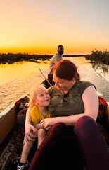 Selbstklebende Fototapeten Orange Tourist bonding with child on a boat in Iraqs picturesque sunset landscape  © Dave