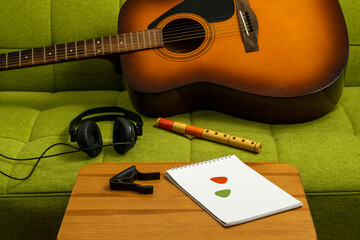 Acoustic guitar on a couch. Acoustic guitar on a green couch, with plectrums, a flute and a capo