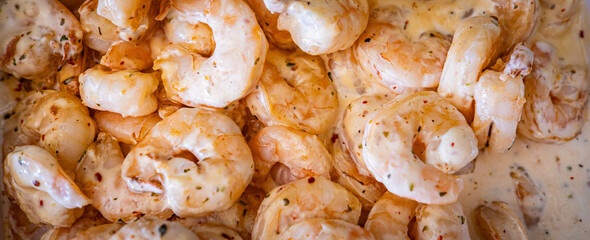 Shrimps background texture in white creamy sauce. A lot of shrimps horizontal banner background. Cooked shrimps.