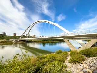 Fototapeta premium Edmonton arch bridge over river with rocky shore and reflections