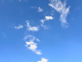 Clear blue sky with scattered fluffy clouds on a sunny day, evoking calm and serenity. Ideal as a...