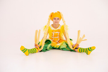 Cheerful girl having fun, dancing and laughing on light background in yellow corn costume with funny facial expression in empty space.