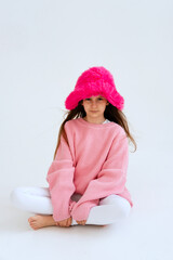 Excited girl model in pink hat posing in studio. Clothes, children's fashion concept. Positive child dancing in studio. vertical