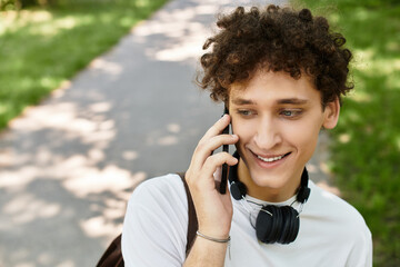 Young man enjoying a sunny day in the park while talking on the phone
