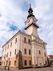 Fototapeta premium Historic town hall in Kežmarok, Slovakia, featuring a tall clock tower with baroque elements, captured under a partly cloudy sky.
