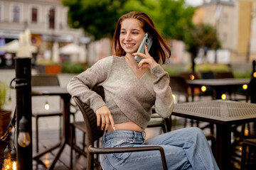 Young Woman With An Umbrella At A Street Cafe Speaking On The Phone