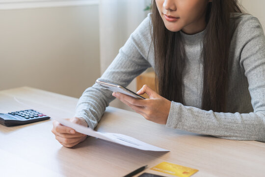Bill pay concept. Online internet banking asian young woman hand holding invoice use mobile smart phone spend scan barcode to transfer to pay money of credit card without cash. Technology of financial