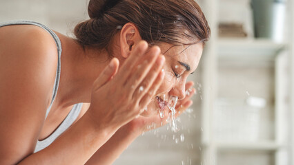 Young woman washing her face in bathroom