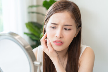 Anti aging, worry puberty asian young woman, stressed girl looking in mirror, allergy presenting an...