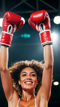 Victorious female boxer celebrates with raised arms under spotlight