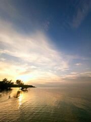 Sunset at sea. Vertical seascape with view of shore, water surface and sky at sunset. Concept of calm and harmony. Inspiring natural view for meditation.